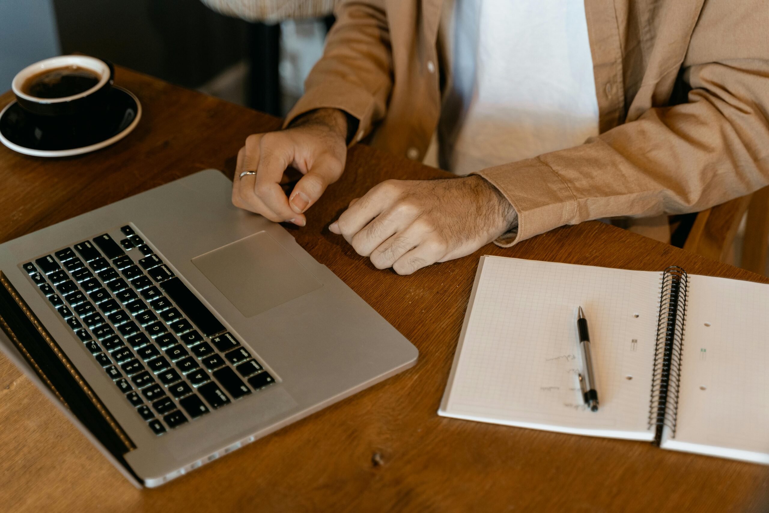 Someone using a laptop with a notebook and pen nearby for why it's important to hire a copywriter