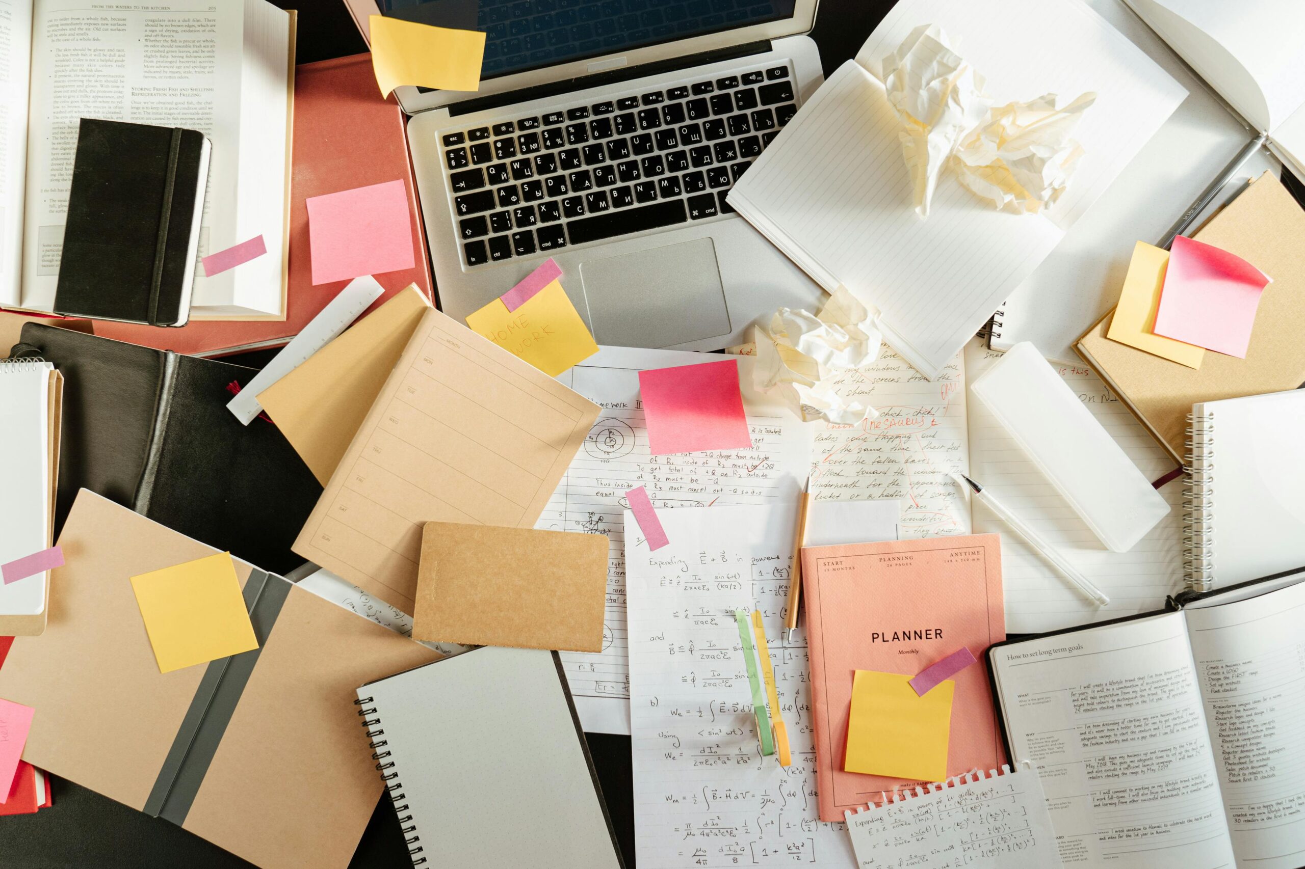 Cluttered desk with marketing materials and laptop